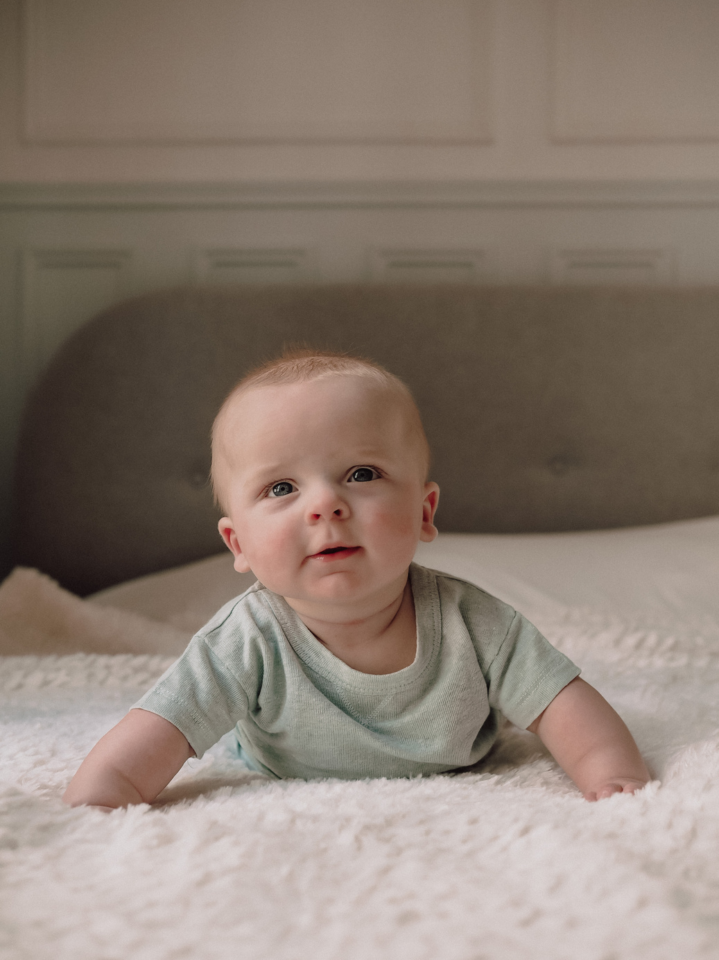 Photo de bébé à plat ventre sur un lit.